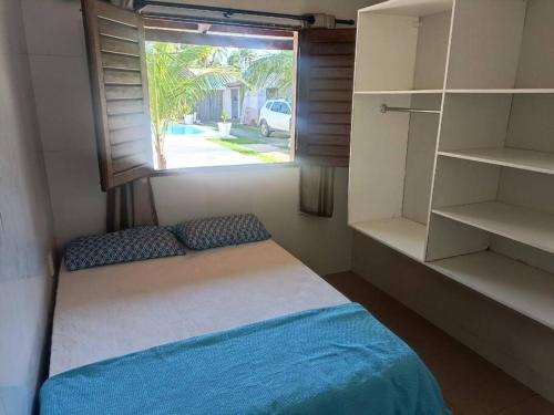 Zimmer mit einem Bett, einem Fenster und Regalen in der Unterkunft Casa em condomínio na praia de Paripueira AL in Paripueira