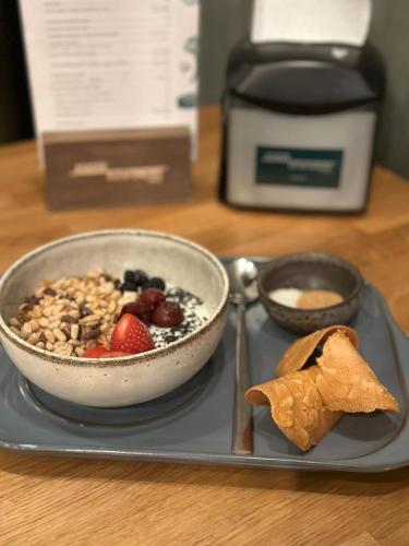 a plate with a bowl of cereal and a bowl of fruit at Hotel Ocamiño in Durango