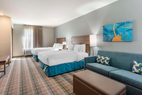 a hotel room with two beds and a couch at MainStay Suites Ocean City West in Ocean City
