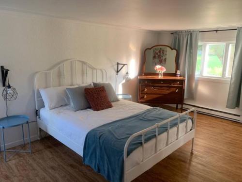 sypialnia z białym łóżkiem, komodą i oknem w obiekcie Chalet de Mimi w mieście Coaticook
