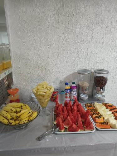 einen Tisch mit Teller mit Lebensmitteln und Obst in der Unterkunft Hotel Buriti da Serra in Itaipava