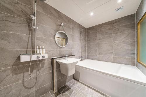 a bathroom with a tub and a sink and a shower at Hotel Bon in Tongyeong