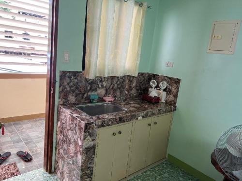 a kitchen counter with a sink and a window at Ria's Pension in Puerto Princesa City