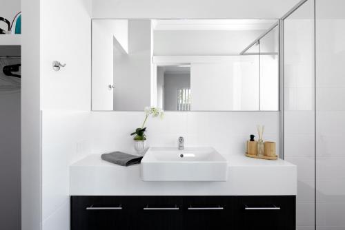 een badkamer met een witte wastafel en een spiegel bij U7/560 Cozy Lovely in Perth
