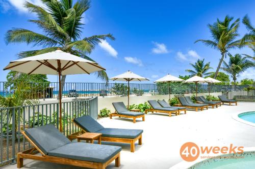 a row of chairs and umbrellas next to a pool at La Belle Bleue direct access to Orient Bay beach swimming pool, 2 bedrooms in Orient Bay
