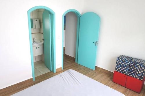 een kamer met twee blauwe deuren en een spiegel bij Casa pertinho da praia com piscina e churrasqueira in Peruíbe