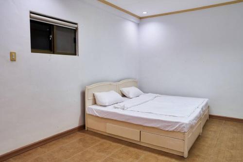 Schlafzimmer mit einem Bett mit weißer Bettwäsche und einem Fenster in der Unterkunft Lovely & Spacious Family House in Tagaytay in Tagaytay