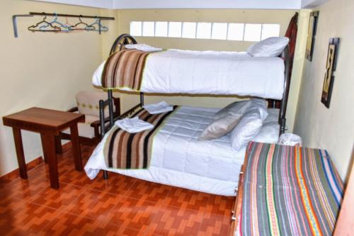 a bedroom with two bunk beds and a table at LA CUSQUEÑITA in Cusco