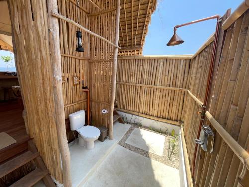 a bathroom with a toilet in a bamboo house at Le Pirate Island - Adults Only in Labuan Bajo