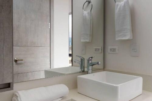 a white bathroom with a sink and a mirror at Apto 2 habitaciones Comfort Kappa in Bogotá