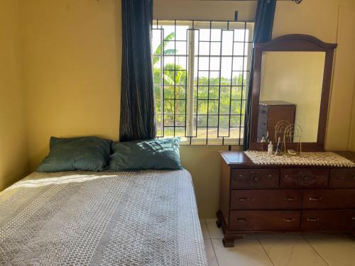 a bedroom with a bed and a dresser and a window at Finest Accommodation Phoenix Park Lot 1317 Phase 4 Portmore St Catherine in Portmore