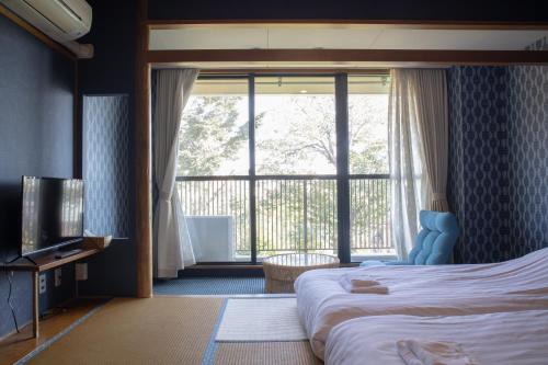 um quarto de hotel com uma cama e uma grande janela em ISOLA Izukogen em Ito