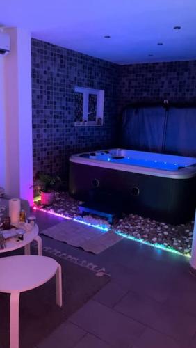 um quarto com uma banheira, uma mesa e luzes violetas em Dream SPA em Vitrolles