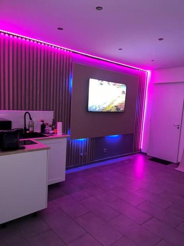 um quarto com luzes roxas e uma televisão na parede em Dream SPA em Vitrolles
