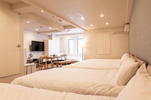 two beds in a room with a kitchen and a table at RIVER CENTRAL HIROSHIMA in Hiroshima