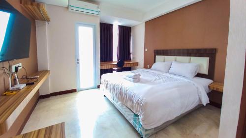 a bedroom with a large white bed and a television at Ayostay at B Residence Serpong in Tjilandak