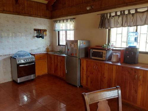 La cuisine est équipée d'une cuisinière, d'un réfrigérateur et d'un four micro-ondes. dans l'établissement Te Ra'a Travel - Cabaña equipada, à Hanga Roa