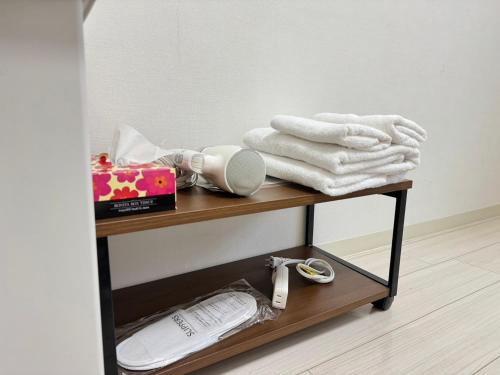 a table with towels on it with a shelf at A&C STAY Shin-Osaka Higashikuchi 83 in Osaka