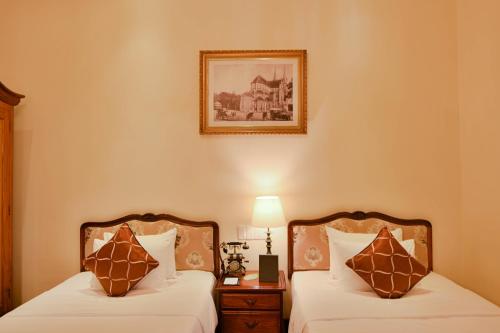 a bedroom with two beds and a picture on the wall at Hotel Grand Saigon in Ho Chi Minh City