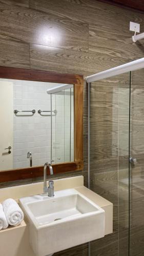 a bathroom with a sink and a glass shower at Castelhana Praia Hotel - Itauna Saquarema in Saquarema
