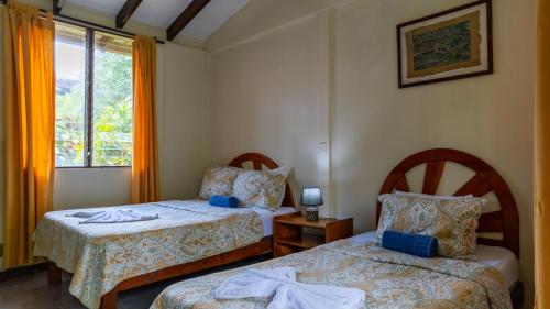 a bedroom with two beds and a window at Diuwak in Dominical