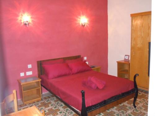 um quarto com uma cama vermelha e almofadas cor-de-rosa em Number 20 em Birgu