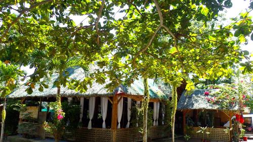 une maison avec un toit de chaume et des fleurs dans l'établissement Island Tiki Paradise Resort, à Panglao