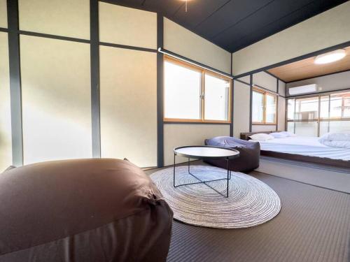a room with a bed and a table and a couch at TasoneUrbanStayOsaka 梅田中津2 in Osaka