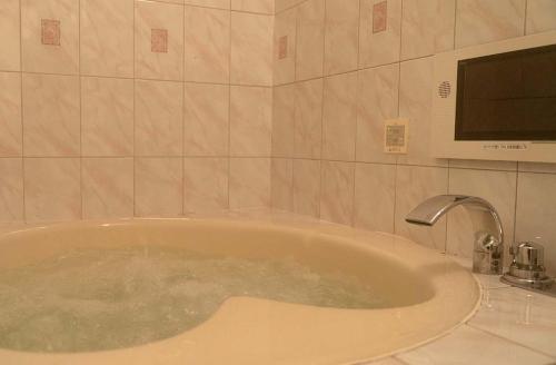 a bath tub in a bathroom with a tv at Hotel Dion ホテル ディオン - Adult Only in Kyoto