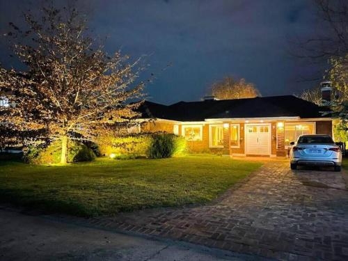 a house with a car parked in the driveway at Villa with exclusive heated and illuminated pool in the best Golf Country Club 18-holes golf course Indoor heated pool of the club Illuminated professional soccer and tennis courts Children's Recreation Market and all types of services in Buenos Aires