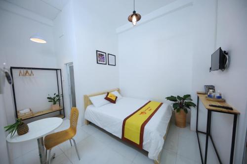 a bedroom with a bed and a table and a chair at HOTEL VĂN THÁI BÌNH in Trà Vinh