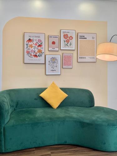 a green couch in a living room with pictures on the wall at LAD Apartment & Homestay Hải Phòng - Hoàng Huy Grand Tower in Hai Phong