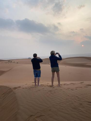 two people standing in the desert taking pictures at Desert Stars Camp in Bidiyah