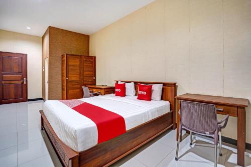 een slaapkamer met een bed, een bureau en een stoel bij OYO 90889 Dkb Residence in Surabaya
