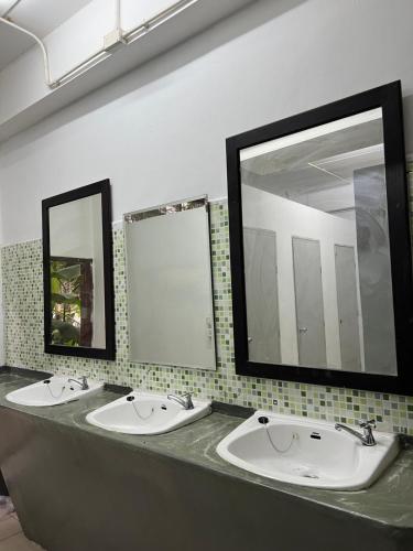 two sinks in a public bathroom with two mirrors at Happiness Hostel in Phra Ae beach