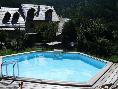 une grande piscine devant une maison dans l'établissement Charmant 2 pièces avec Balcon & Parking à 300m des Pistes - Piscine, Wi-Fi et Jardin - FR-1-762-13, à Saint-Chaffrey