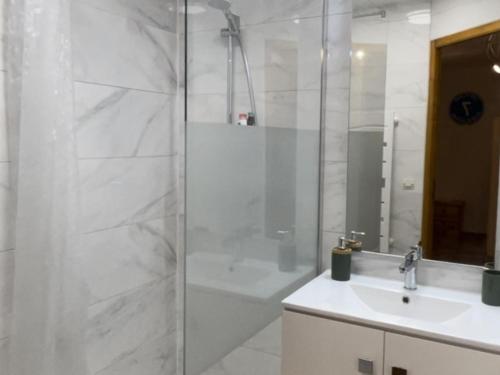 une salle de bain blanche avec une douche et un lavabo dans l'établissement Appartement charme pieds des pistes avec terrasse et WIFI inclus - FR-1-505-197, à Notre-Dame-de-Bellecombe