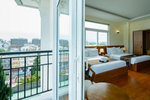a hotel room with two beds and a balcony at Bombo DaLat Hotel in Da Lat