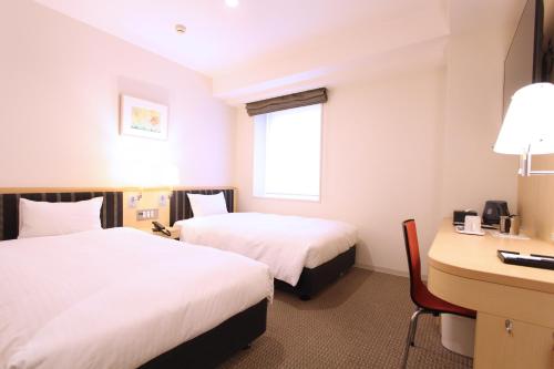 a hotel room with two beds and a desk at KOKO HOTEL Sendai Station West in Sendai