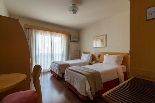 a hotel room with two beds and a window at Intercity Interative São Paulo Jardins in São Paulo