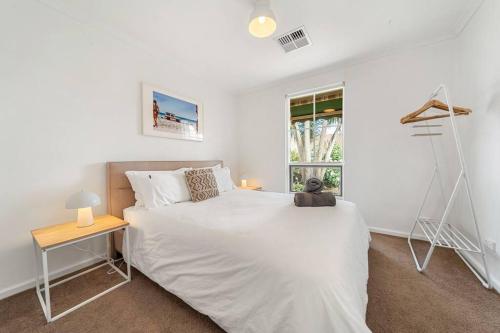 een witte slaapkamer met een wit bed en een raam bij Sunset Soirée - WiFi Beach Family in Sellicks Beach