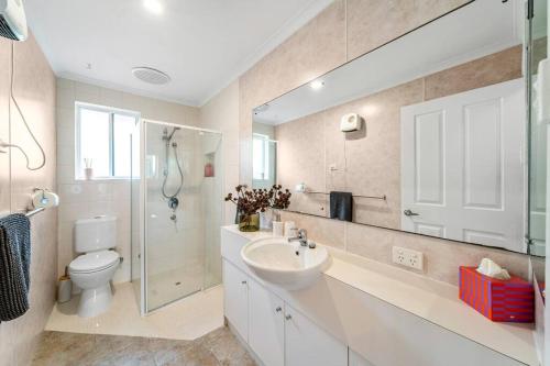 een badkamer met een wastafel, een toilet en een spiegel bij Sunset Soirée - WiFi Beach Family in Sellicks Beach