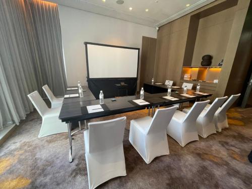 a conference room with a long table and white chairs at Le Meridien Taipei in Taipei
