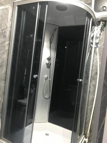 a shower with a glass door in a bathroom at Cottage town D&N in Karakol