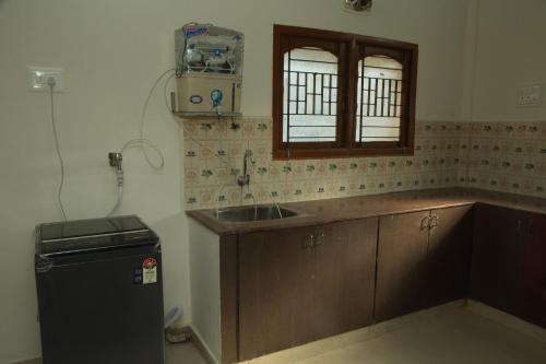 a kitchen with a sink and a small refrigerator at IZI APOLLO STAY in Chennai
