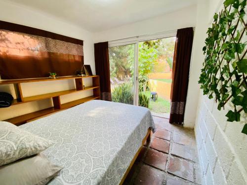 ein Schlafzimmer mit einem Bett und einem großen Fenster in der Unterkunft Bungalito en Cuernavaca in Cuernavaca