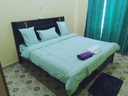 ein Schlafzimmer mit einem großen Bett mit einer lila Tasche darauf in der Unterkunft BONNY KINGs FARMSTAY in Kiambu