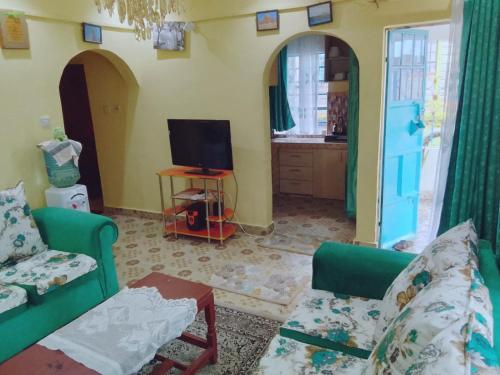 Sala de estar con 2 sillas verdes y TV en BONNY KINGs FARMSTAY, en Kiambu