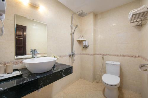 a bathroom with a sink and a toilet and a mirror at Silk Hanoi Moment Hotel & Spa in Hanoi