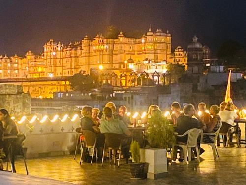 a group of people sitting at tables in front of a building at Kotra Haveli A Boutique Hotel by Lake Pichola in Udaipur